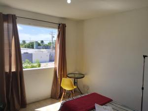 1 dormitorio con ventana y silla amarilla en Pousada Jardins Campista, en Macaé