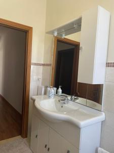 La salle de bains est pourvue d'un lavabo blanc et d'un miroir. dans l'établissement Appartamento - Porto San Giorgio, à Porto San Giorgio
