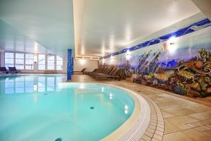 a large swimming pool in a building with a mural at Grafenberg Resort by Alpeffect Hotels in Wagrain