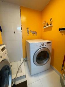 - un lave-linge dans une buanderie aux murs jaunes dans l'établissement Hermoso apartamento con piscina., à La Estrella