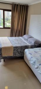 2 camas en una habitación con ventana en Apartamento Perfeito águas claras en Águas Claras