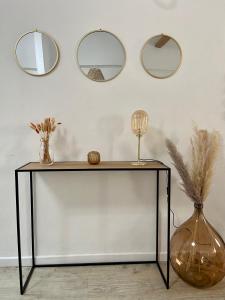 a table with a vase and three mirrors on the wall at Le Refuge du Port, parking privé gratuit in La Ciotat