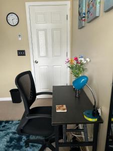 una scrivania con sedia e un tavolo con un vaso di fiori di Cozy Space a Creedmoor