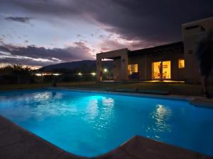 a swimming pool at night with a villa in the background at Sol de las Sierras Zonda PREVIAJE in Zonda