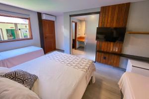 a bedroom with two beds and a flat screen tv at Pousada Novo Prado in Prado