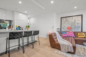 a kitchen and living room with a bar and chairs at StayAU Modern 2BR Townhouse w/ pool in Oakleigh