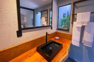 a bathroom with a black sink and two windows at Pousada Novo Prado in Prado