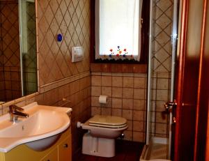 プンタ・アーラにあるAppartamenti Pian d'Almaのバスルーム(トイレ、洗面台付)、窓が備わります。