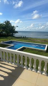 una piscina accanto a un balcone con vista sull'oceano di Emerald Luxe Suites a Big Corn Island