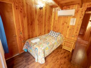 um pequeno quarto com uma cama num quarto de madeira em Hotel Catripulli em Pucón