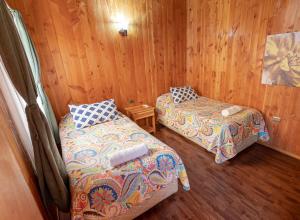 two beds in a room with wooden walls at Hotel Catripulli in Pucón