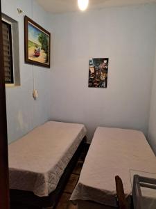 two beds in a room with a picture on the wall at Pensão da Celia in Ribeirão Preto