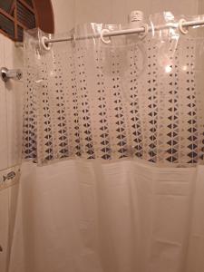 a shower with a white shower curtain in a bathroom at Pensão da Celia in Ribeirão Preto