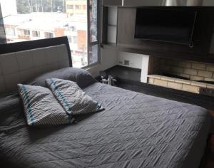 1 dormitorio con 1 cama con 2 almohadas y TV en Casa de Huéspedes Santa María Hotel, en Bogotá