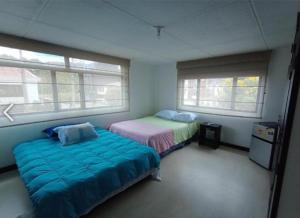 1 Schlafzimmer mit 2 Betten und 2 Fenstern in der Unterkunft Casa de Huéspedes Santa María Hotel in Bogotá