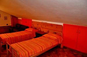 two beds in a room with red cabinets at Appartamenti Pian d'Alma in Punta Ala