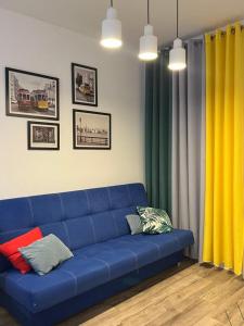 - un canapé bleu dans le salon avec des oreillers colorés dans l'établissement Apartament Chiara, à Oleśnica
