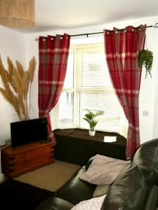 a living room with a couch and a window with red curtains at Fern Villa in Conwy