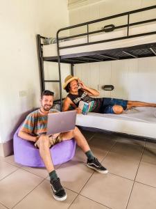 two people sitting on bunk beds with a laptop at Nomads Airlie Beach in Airlie Beach
