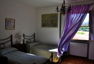 a bedroom with two beds and a window with purple curtains at Appartamenti Pian d'Alma in Punta Ala