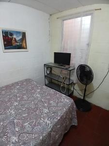 ein Schlafzimmer mit einem Bett und einem Schreibtisch mit einem Laptop in der Unterkunft Santa Tecla Acogedora Guest House in Nueva San Salvador