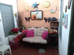 ein Wohnzimmer mit einem Sofa und einer Wand mit Schmetterlingen in der Unterkunft Santa Tecla Acogedora Guest House in Nueva San Salvador