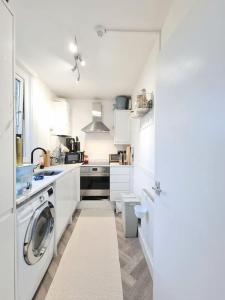 una cocina blanca con lavadora. en Fresh and Sparkling - Free Parking, en Crystal Palace