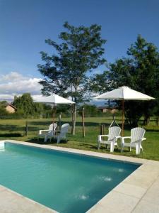 a group of chairs and umbrellas next to a pool at INTI MAYU Cabañas in Mina Clavero