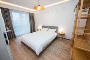Un dormitorio con una cama blanca y una escalera en EGO Apartment en Târgu Mureș