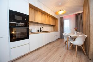 una cocina con armarios blancos y una mesa con sillas. en EGO Apartment en Târgu Mureș