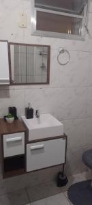 a bathroom with a white sink and a mirror at Apartamento Tá Querendo Praia! in Guarujá
