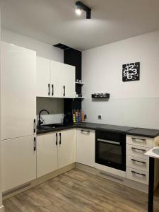 une cuisine avec des armoires blanches et un appareil noir dans l'établissement Apartament Chiara, à Oleśnica