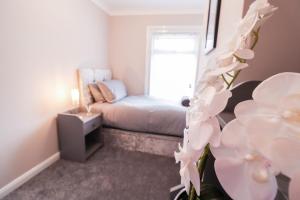 a small bedroom with a bed and flowers in the foreground at Great 3 Bed Refurbished House in Colchester