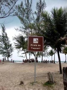 a sign on a beach with people in the background at Beira Mar Residencial in Guaibim