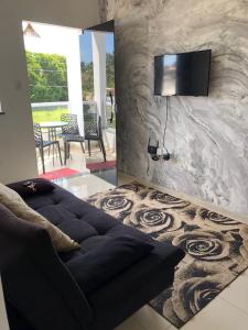 a living room with a couch and a tv on a wall at Beira Mar Residencial in Guaibim