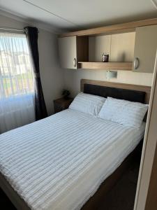 a bedroom with a large white bed with a window at Ranworth - Haven Holiday Park in Caister-on-Sea