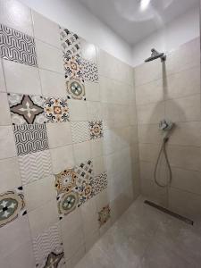 La salle de bains est pourvue d'une douche et de carrelage sur le mur. dans l'établissement Apartament Chiara, à Oleśnica