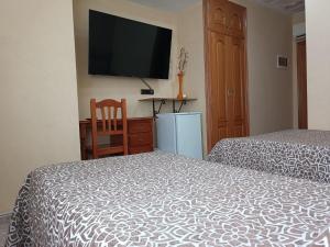 - une chambre avec 2 lits et une télévision murale dans l'établissement Hotel Beatriz, à Burriana