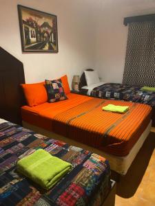 2 Betten in einem Zimmer mit orangefarbener Bettwäsche in der Unterkunft Casa Santiago Son in Antigua Guatemala