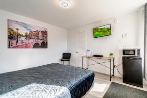 1 dormitorio con cama, escritorio y microondas en Motel Saint Bruno, en Saint-Bruno-de-Montarville