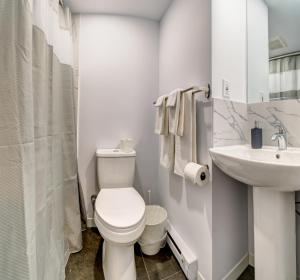 a white bathroom with a toilet and a sink at Motel Saint Bruno in Saint-Bruno-de-Montarville