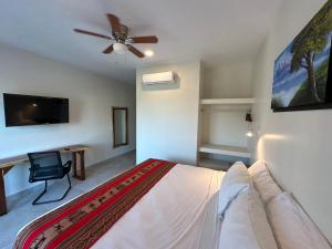 1 dormitorio con 1 cama, ventilador de techo y escritorio en Oneiro Suites with Sea View en Mahahual