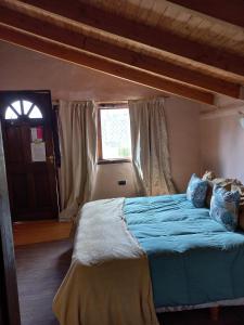 um quarto com uma cama com lençóis azuis e uma janela em Cabañas Los Nonos em El Bolsón