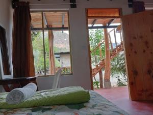 1 dormitorio con ventanas, 1 cama y una escalera en Cabaña Tzanjuyu en San Juan La Laguna