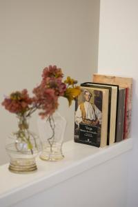 a shelf with books and a vase with flowers on it at My Sicily Home - Casa con giardino in Salemi