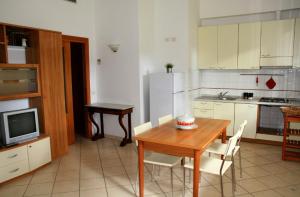 a kitchen with a wooden table and a refrigerator at Appartamenti Pian d'Alma in Punta Ala