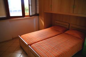 a bedroom with a bed with an orange striped sheets at Appartamenti Pian d'Alma in Punta Ala