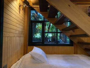 a bedroom with a bed with a staircase and two windows at Casa Murta in Chaitén