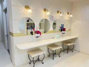 a bathroom with a sink and two stools and mirrors at Cafe&Hostel きみといちご in Osaka