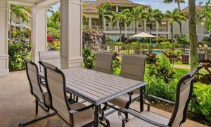 Una mesa y sillas en un patio con piscina. en Ground Floor Luxury Penthouse in Poipu Kai, en Koloa